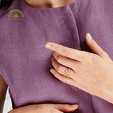 Close-up of a hand wearing two dainty gold rings on a purple fabric background