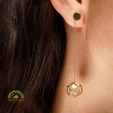 Gold geometric dodecahedron earring worn on an ear with dark hair.