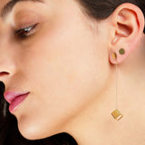 Close-up of a woman wearing gold earrings with a geometric hexahedron design, part of the on a roll series.