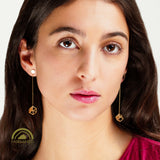Close-up of a woman wearing gold hexahedron earrings with a Fairmined logo.