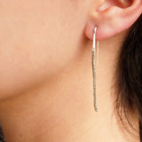 Close-up of a person wearing a thin, textured zig zag earring.