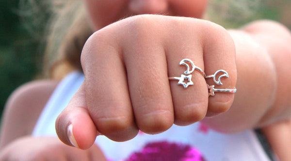 Hand of a child showing moon and star rings on her fingers