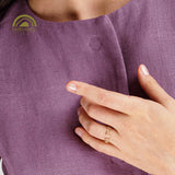 Close-up of a hand wearing a gold ring on a purple fabric background with Fairminded logo.