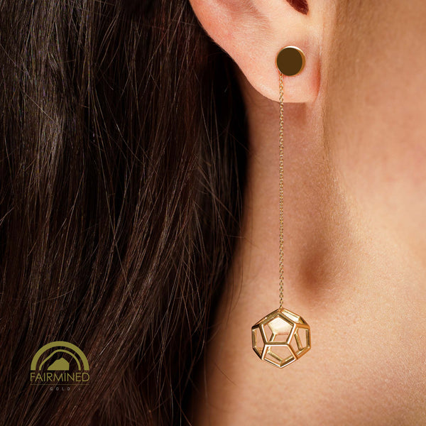 Gold geometric dodecahedron earring worn on an ear with dark hair.