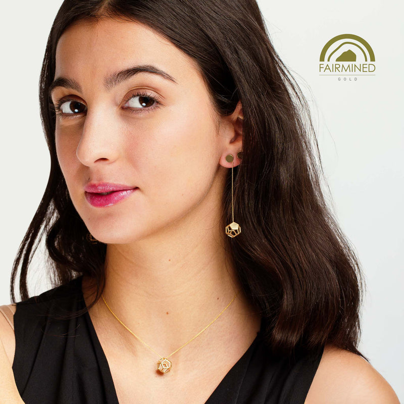 Woman wearing gold earrings and necklace with Fairmined logo.