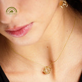 Close-up of a person wearing a gold necklace with a geometric dodecahedron pendant.