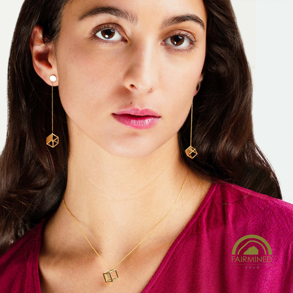 Woman wearing gold earrings and necklace with Fairmined logo